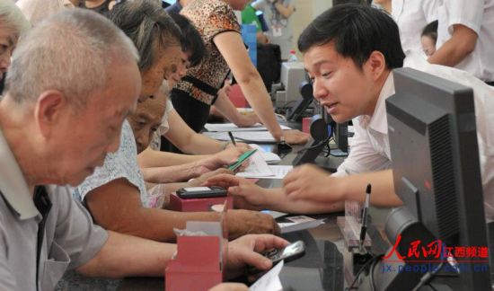 南昌市東湖區(qū)和市民政局工作人員向居家老人介紹專用手機(jī)如何使用。