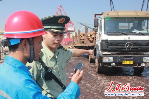 圖為執(zhí)勤人員正向碼頭工人現(xiàn)場(chǎng)演示政務(wù)微信智能管控功能（林錦瑜 攝）