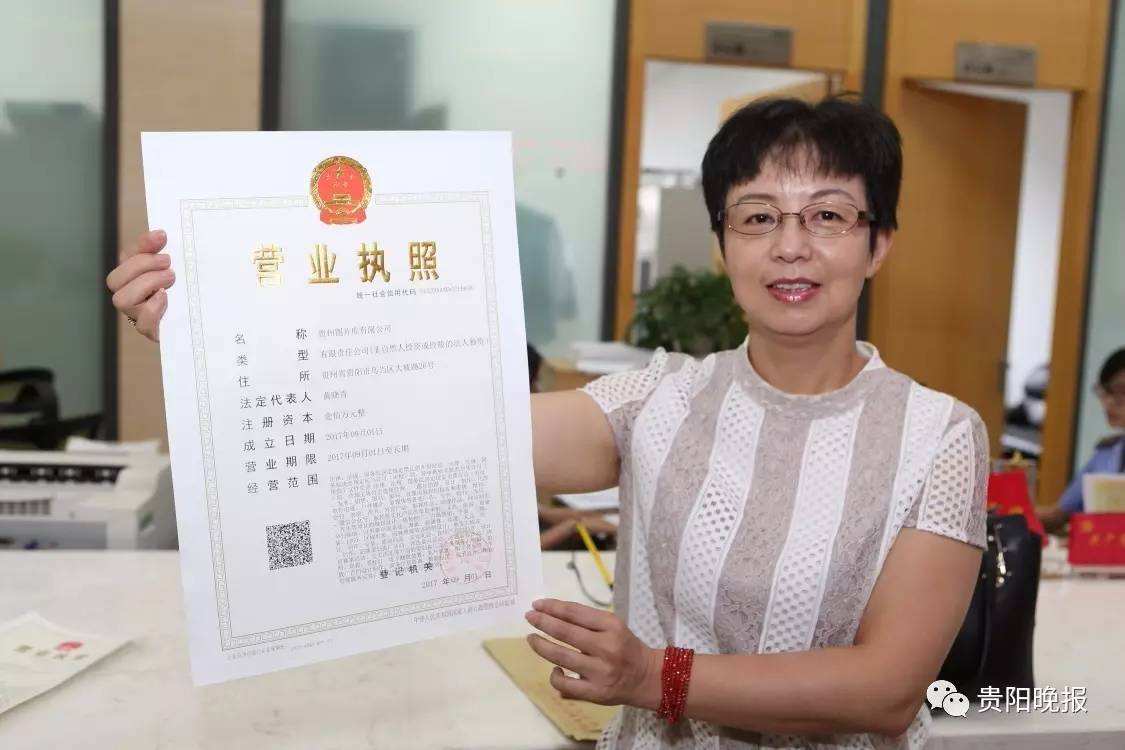 貴州圖片庫有限公司法定代表人黃曉青從貴州省工商局駐省政務(wù)服務(wù)中心首席代表周立新手中接過加載統(tǒng)一社會信用代碼的營業(yè)執(zhí)照