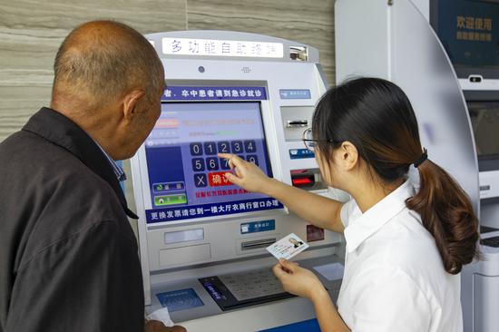 服務(wù)人員通過掛號自助機(jī)為老人預(yù)約專家。潘迎霞 攝